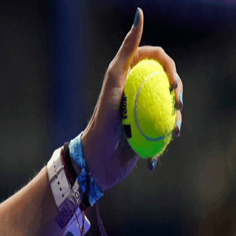 High hand holding a padel ball in the left hand.