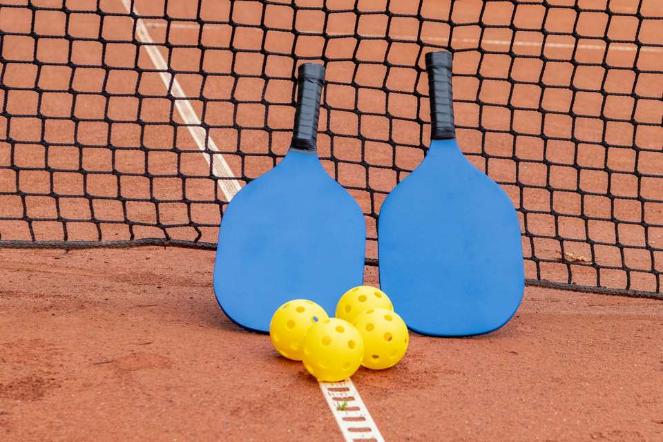 A pickleball paddle and ball on an open court